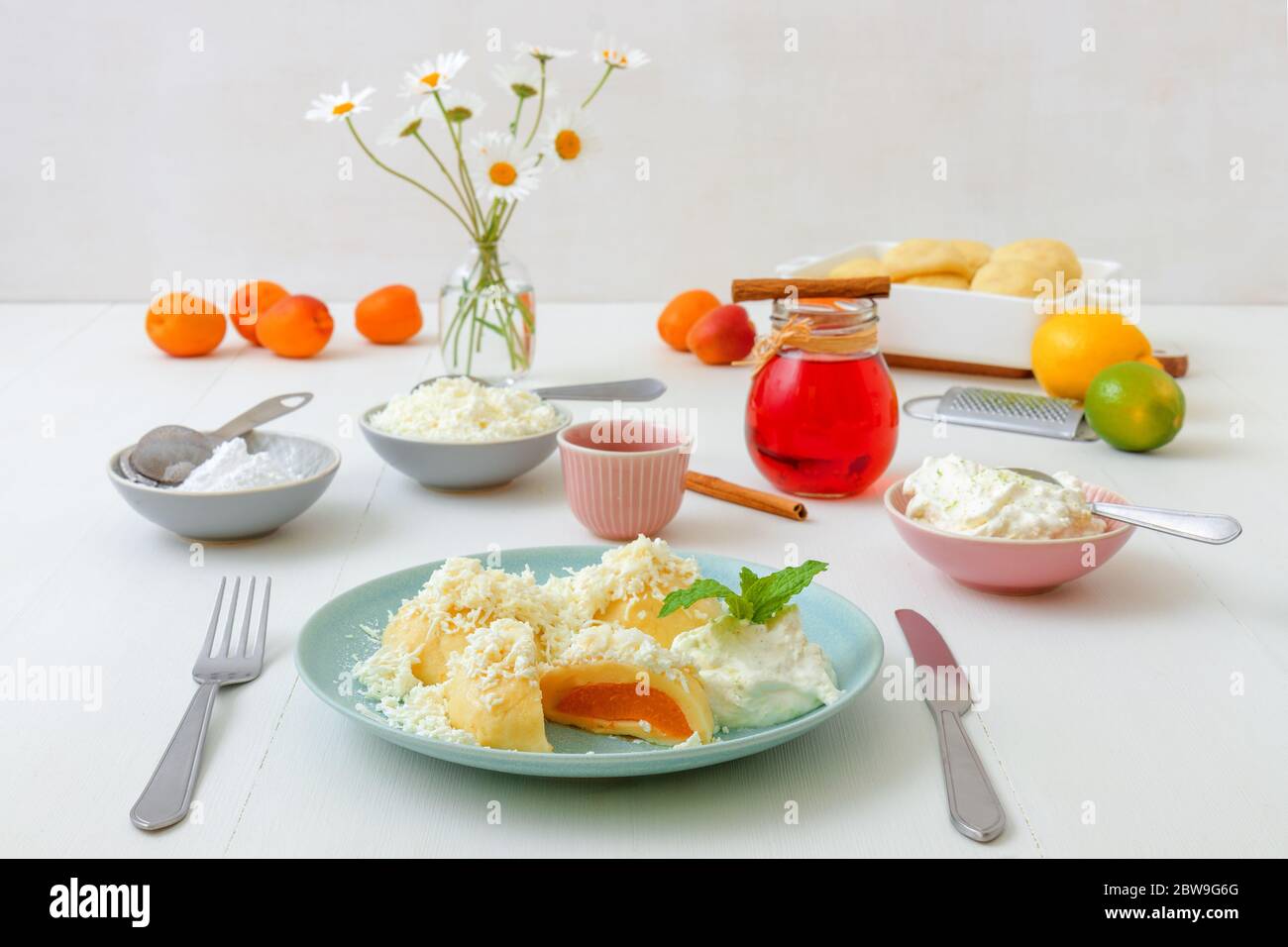 Boulettes de fruits farcies aux abricots, saupoudrées de fromage cottage et de sucre, recouvertes de beurre fondu, de crème fraîche et de zeste de lime râpé Banque D'Images