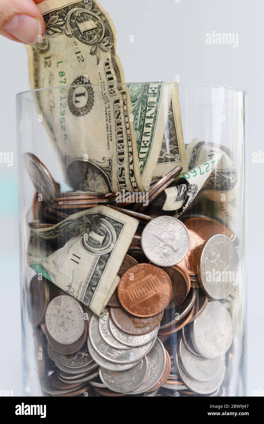 Gros plan des doigts de retirer un billet d'un dollar de la jarre avec l'américain cents et billets Banque D'Images