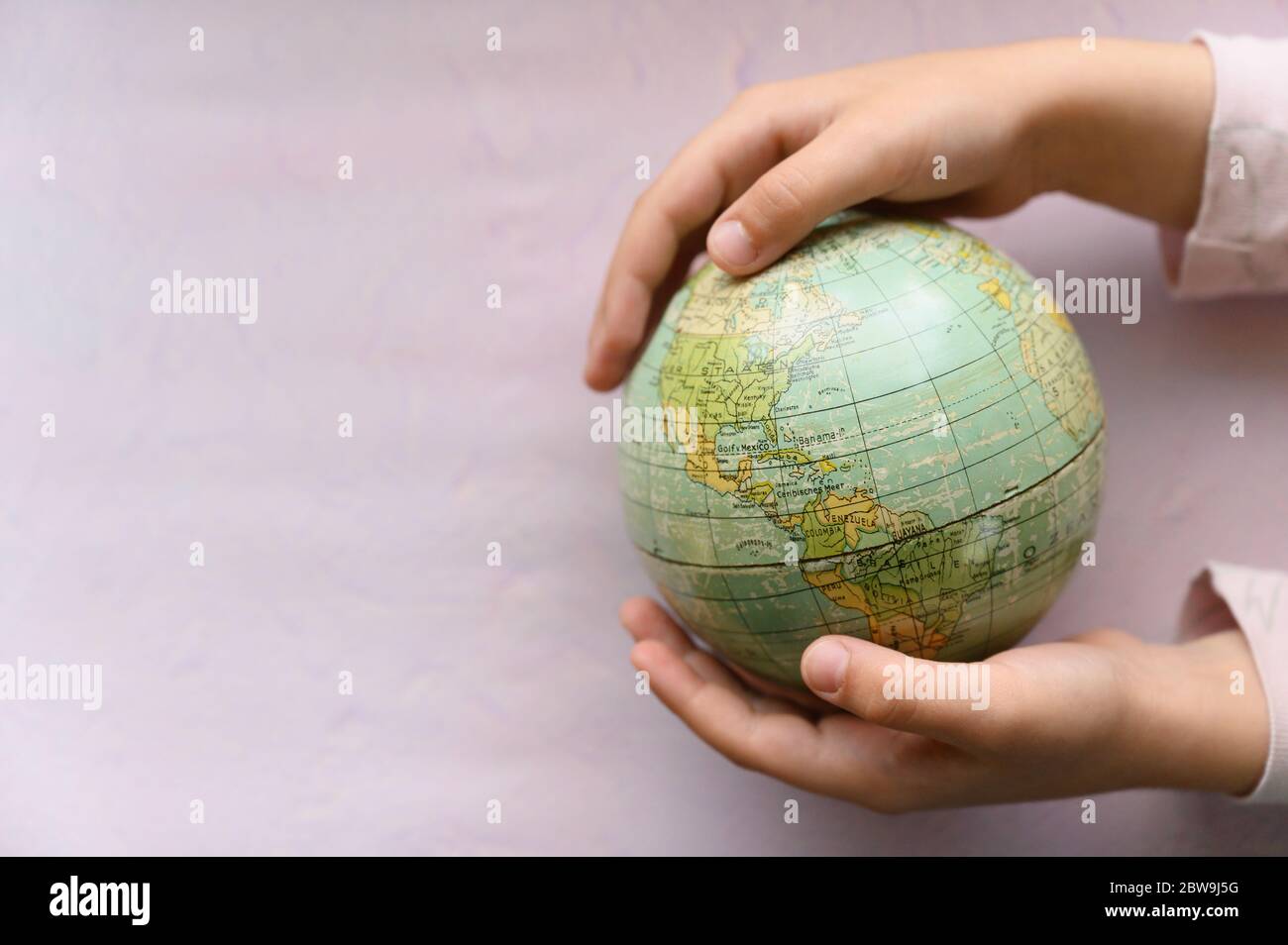 Gros plan des filles (6-7) mains tenant le globe Banque D'Images