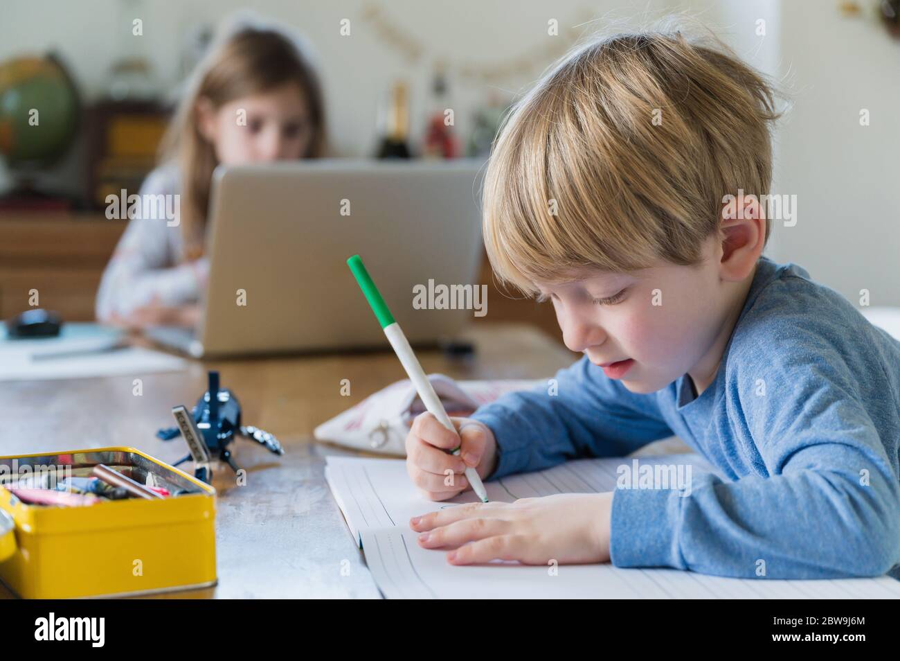 Garçon (4-5) et fille (6-7) faisant leurs devoirs à table Banque D'Images