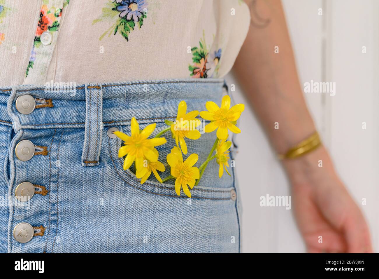 Gros plan d'une femme avec des fleurs jaunes dans une poche Jean Banque D'Images