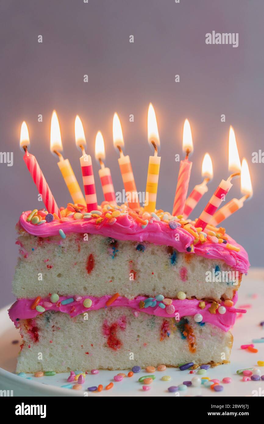 Tranche de gâteau d'anniversaire avec bougies allumées Banque D'Images