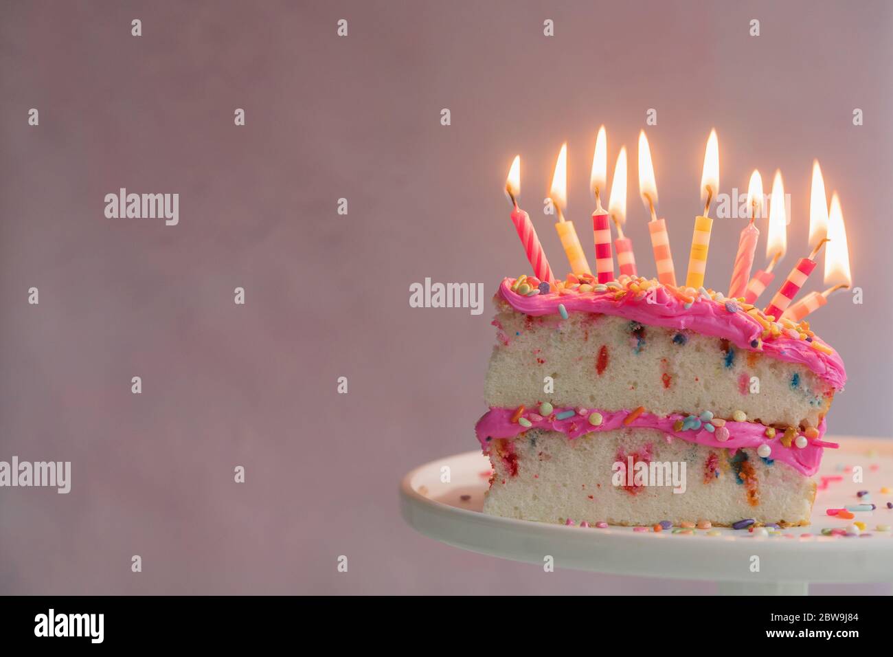 Tranche de gâteau d'anniversaire avec bougies allumées Banque D'Images