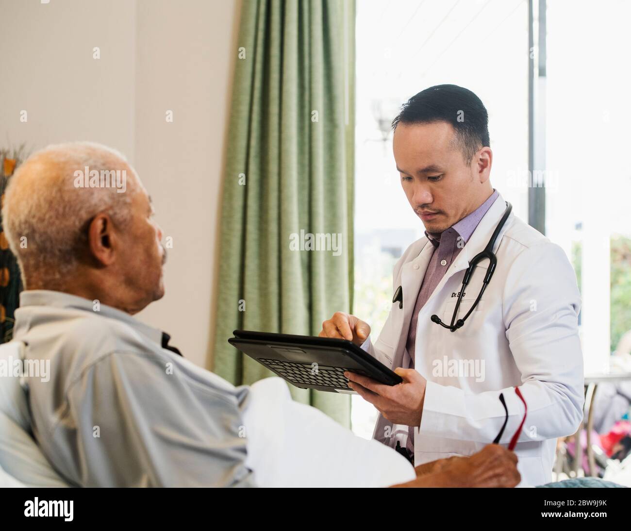 Médecin utilisant une tablette lors de la visite d'un homme âgé dans une maison de soins infirmiers Banque D'Images