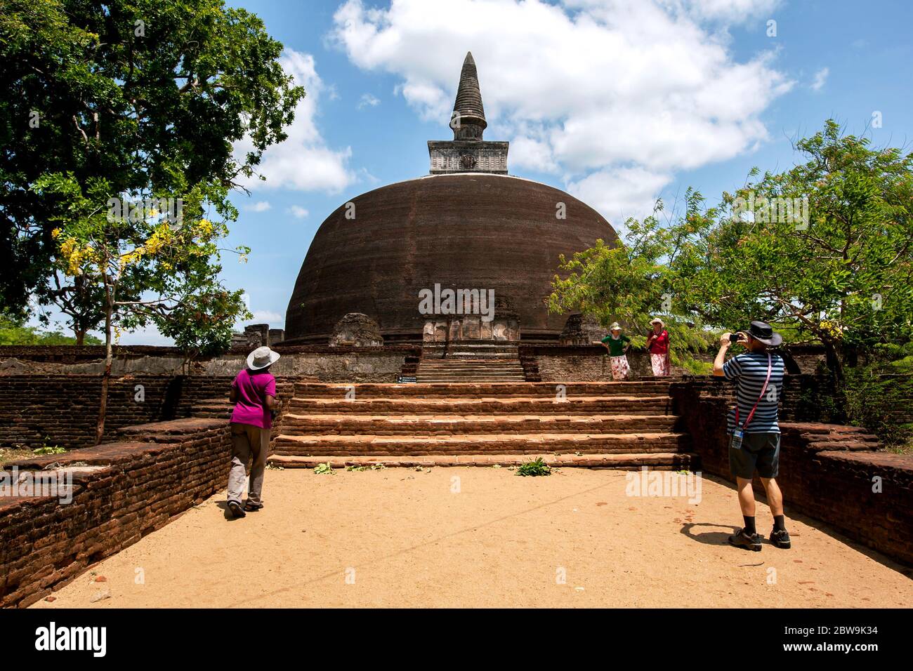 Les touristes admirent le Rankot Vihara sur le site antique de Polonnaruwa au Sri Lanka. Ce dagoba est fait de briques rouges. Banque D'Images