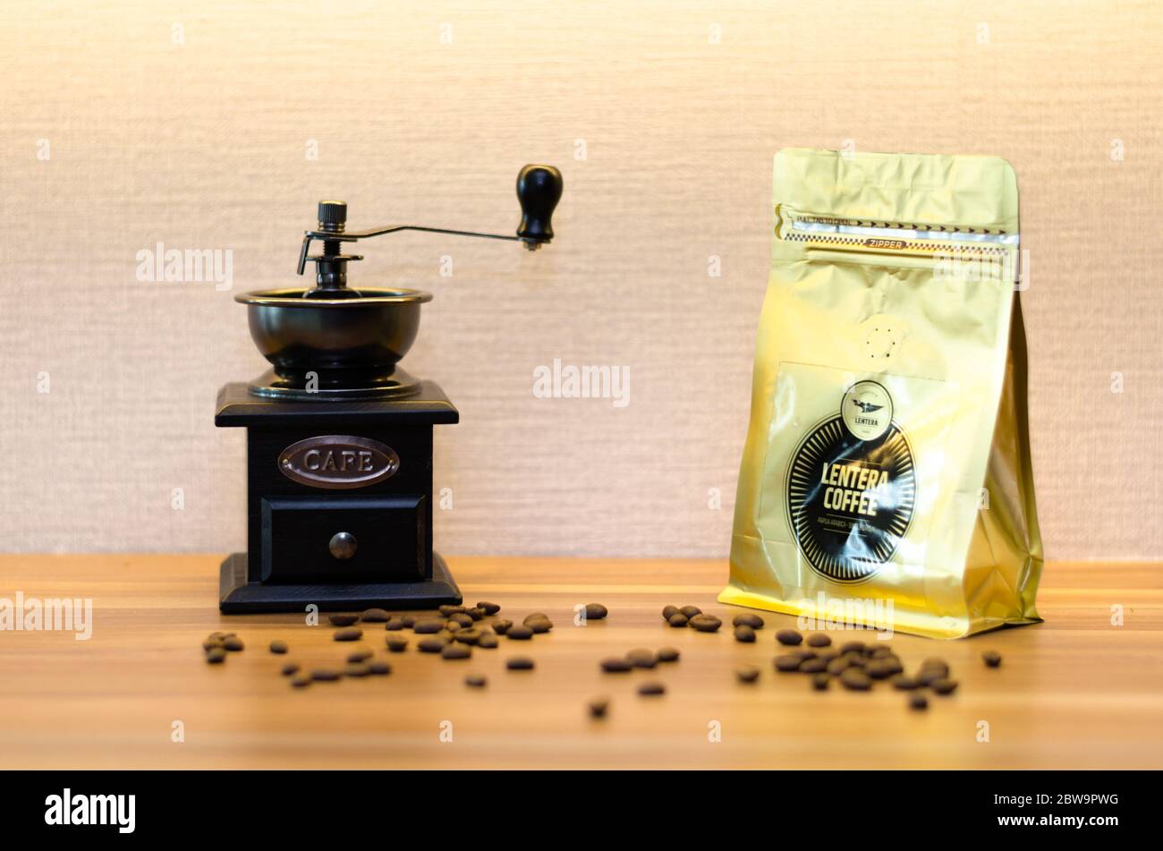 Un moulin à café avec un tiroir ouvert et des grains de café désordonnés sur une table en bois. Banque D'Images