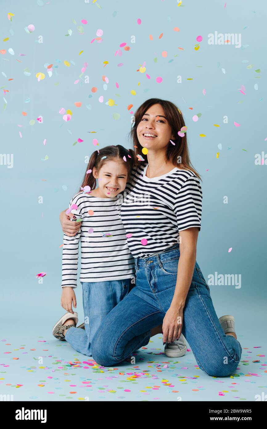 Bonne maman et fille posant dans les mêmes vêtements sous la douche confetti Banque D'Images