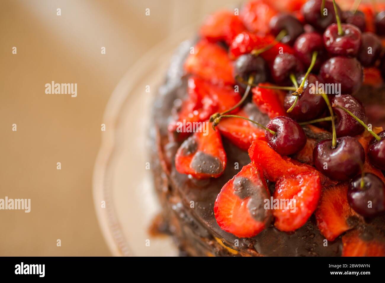 Gâteau au chocolat maison traditionnel dessert sucré avec glaçage brun, cerises, framboise, cassis sur fond de bois vintage. Photo de nourriture sombre Banque D'Images