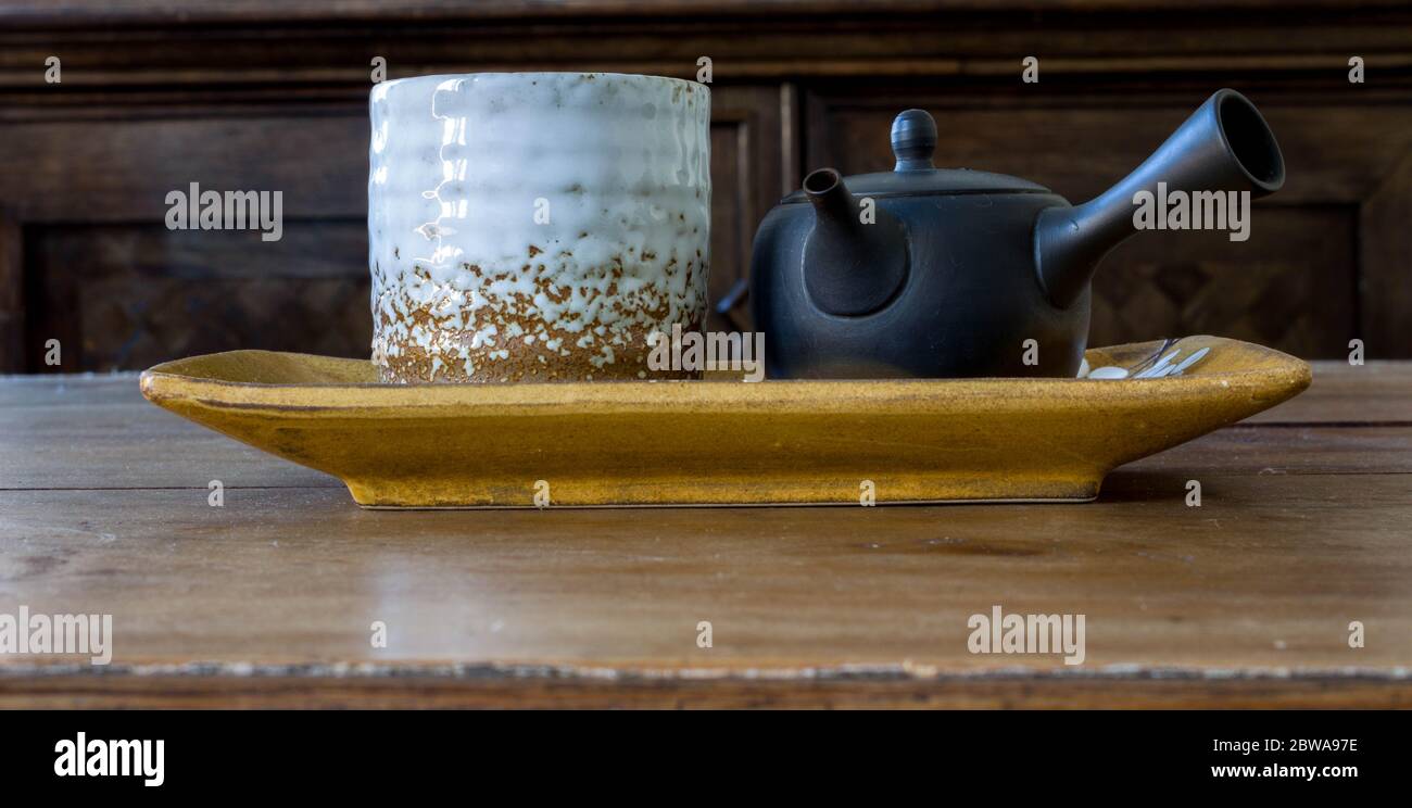 Tasse de thé en céramique blanche avec petite théière noire sur plaque d'orchidées en céramique et table en bois. Véritable culture chinoise du thé vert. Cérémonie de Gongfucha Banque D'Images