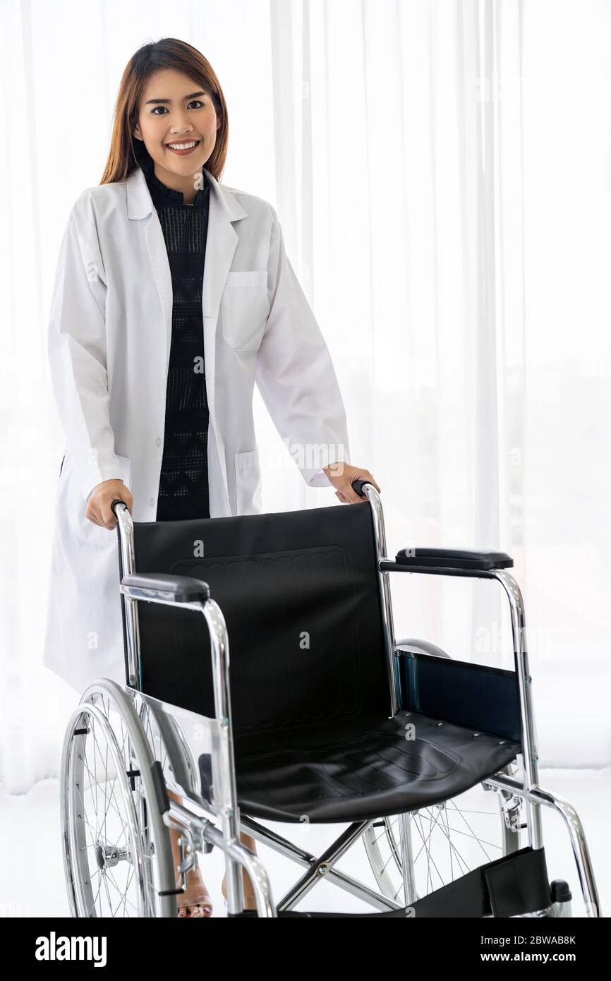 Portrait of female doctor holding medical fauteuil roulant professionnel dans la salle d'examen clinique de l'hôpital Banque D'Images