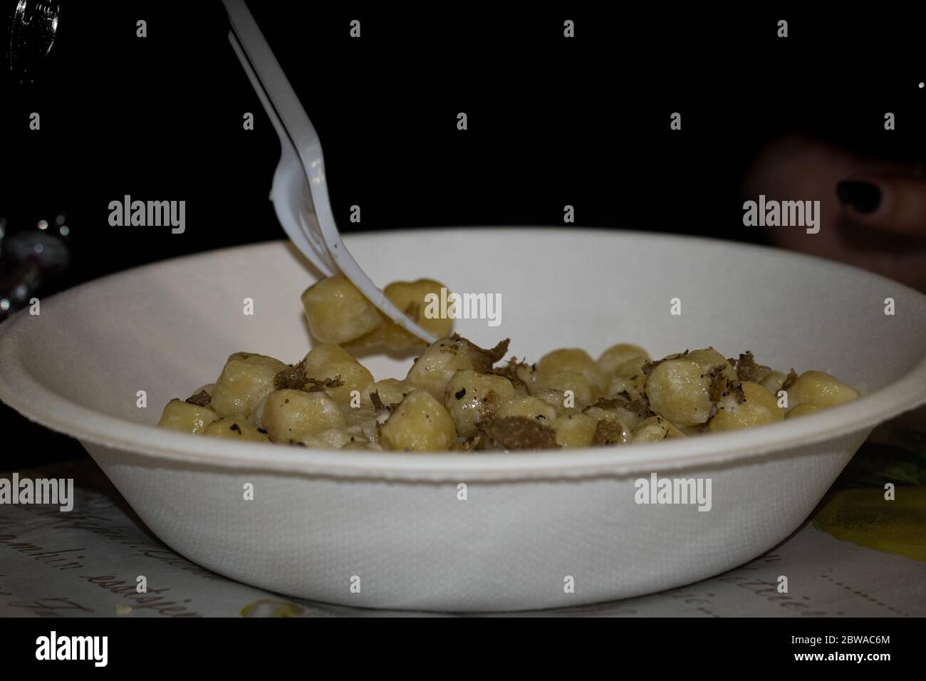 gros plan d'une plaque en plastique blanc avec une fourchette toujours en plastique blanc et à l'intérieur de la plaque gnocchi avec des flocons de truffe Banque D'Images