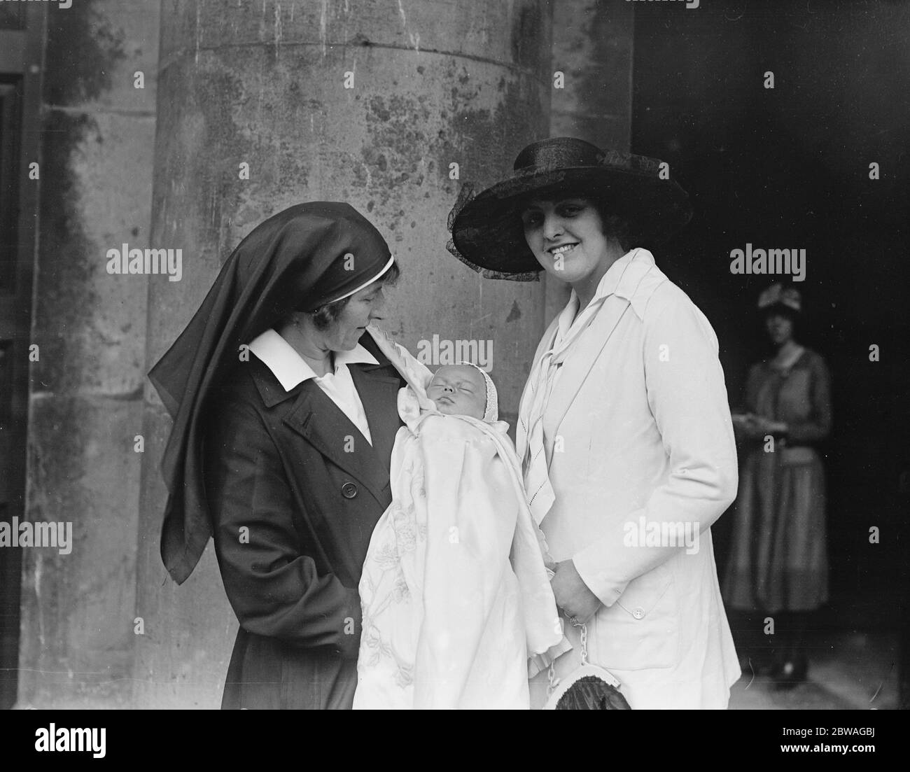 Une infirmière tient le fils de l'acteur Lupino Lane à son baptême à l' église Saint-George , Bloomsbury , Londres , tandis que sa fière mère regarde sur . années 1920 Banque D'Images Une infirmière tient le fils de l'acteur Lupino Lane à son baptême à l' église Saint-George , Bloomsbury , Londres , tandis que sa fière mère regarde sur . années 1920 Banque D'Images