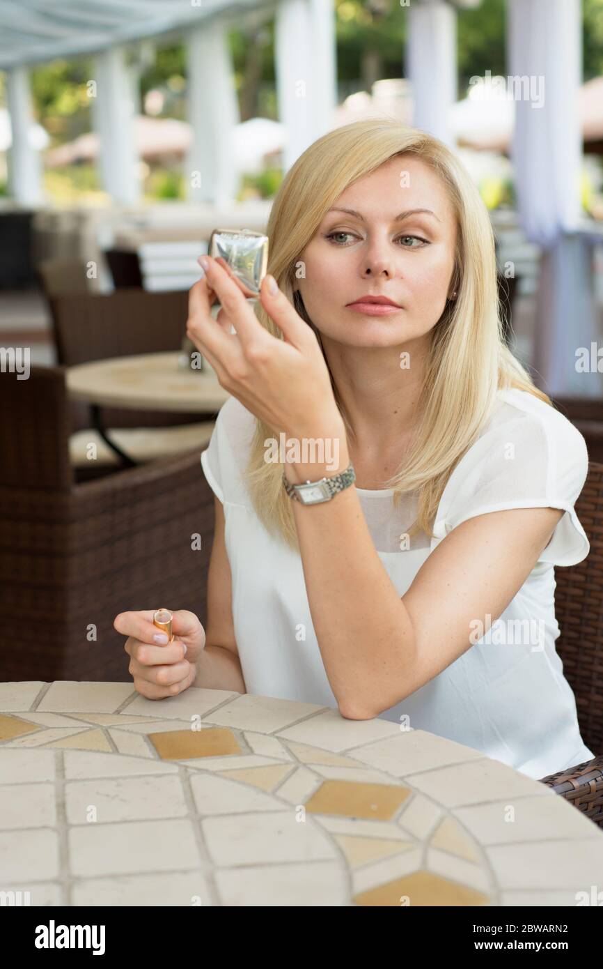 Belle femme est assise dans un café et regardant dans le miroir Banque D'Images