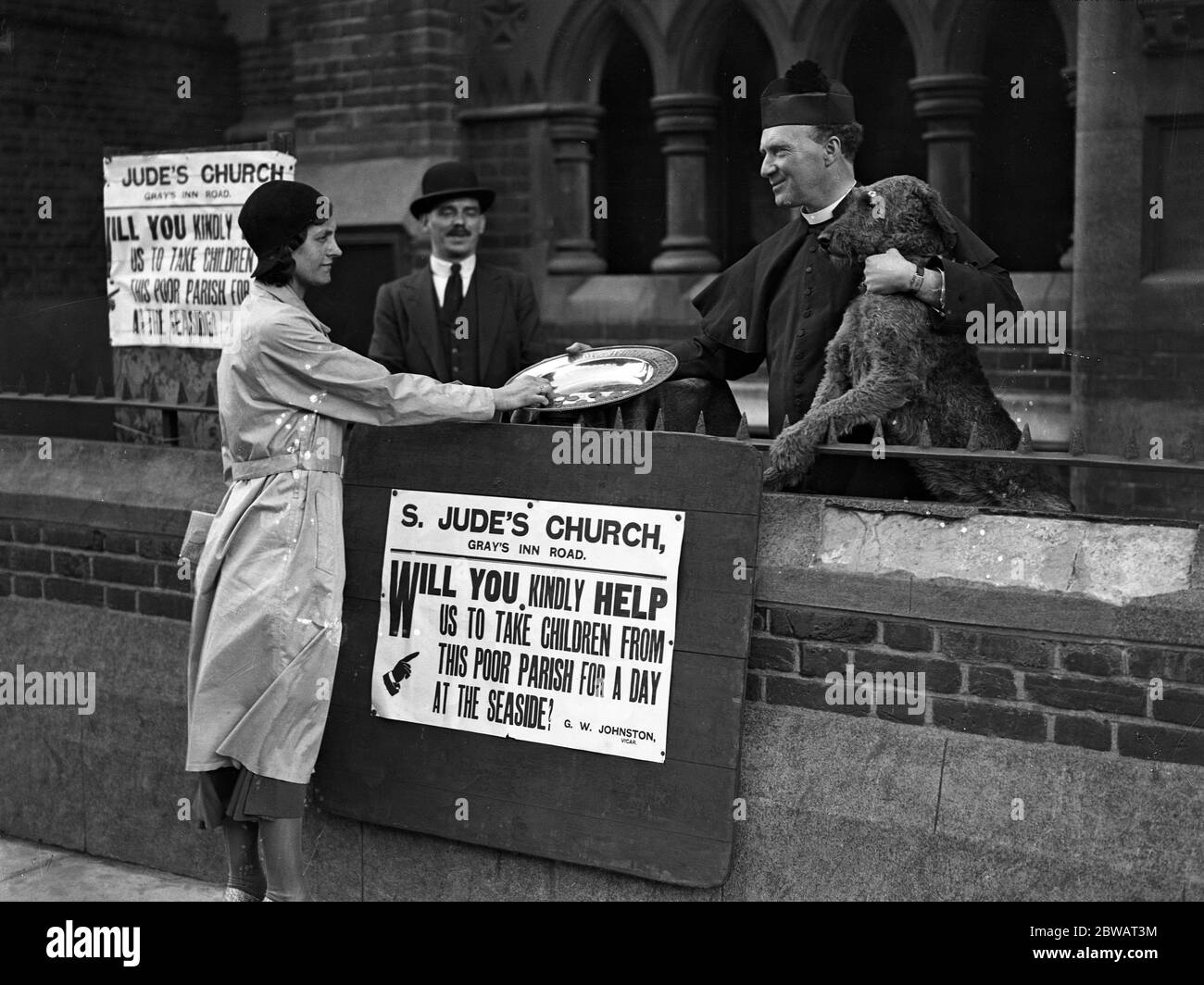 Le révérend G W Johnston , vicaire de St Jude , Gray's Inn Road , Londres , recevant , en personne à la porte de son église , des abonnements pour offrir une journée au bord de mer aux enfants pauvres de son district . 1er juillet 1932 Banque D'Images