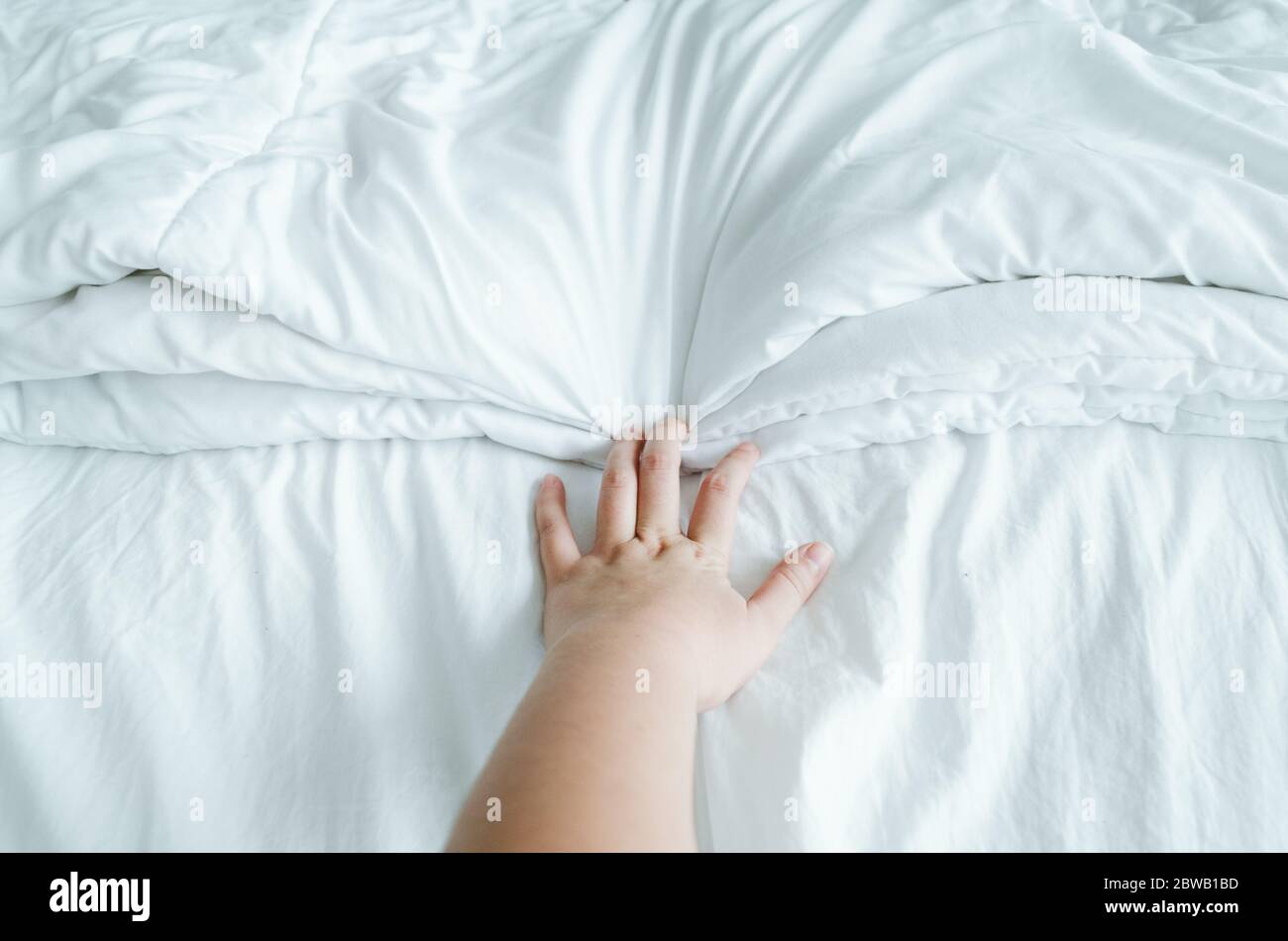 Main exprimant des émotions tout en tenant des feuilles blanches froissées dans le lit. Banque D'Images