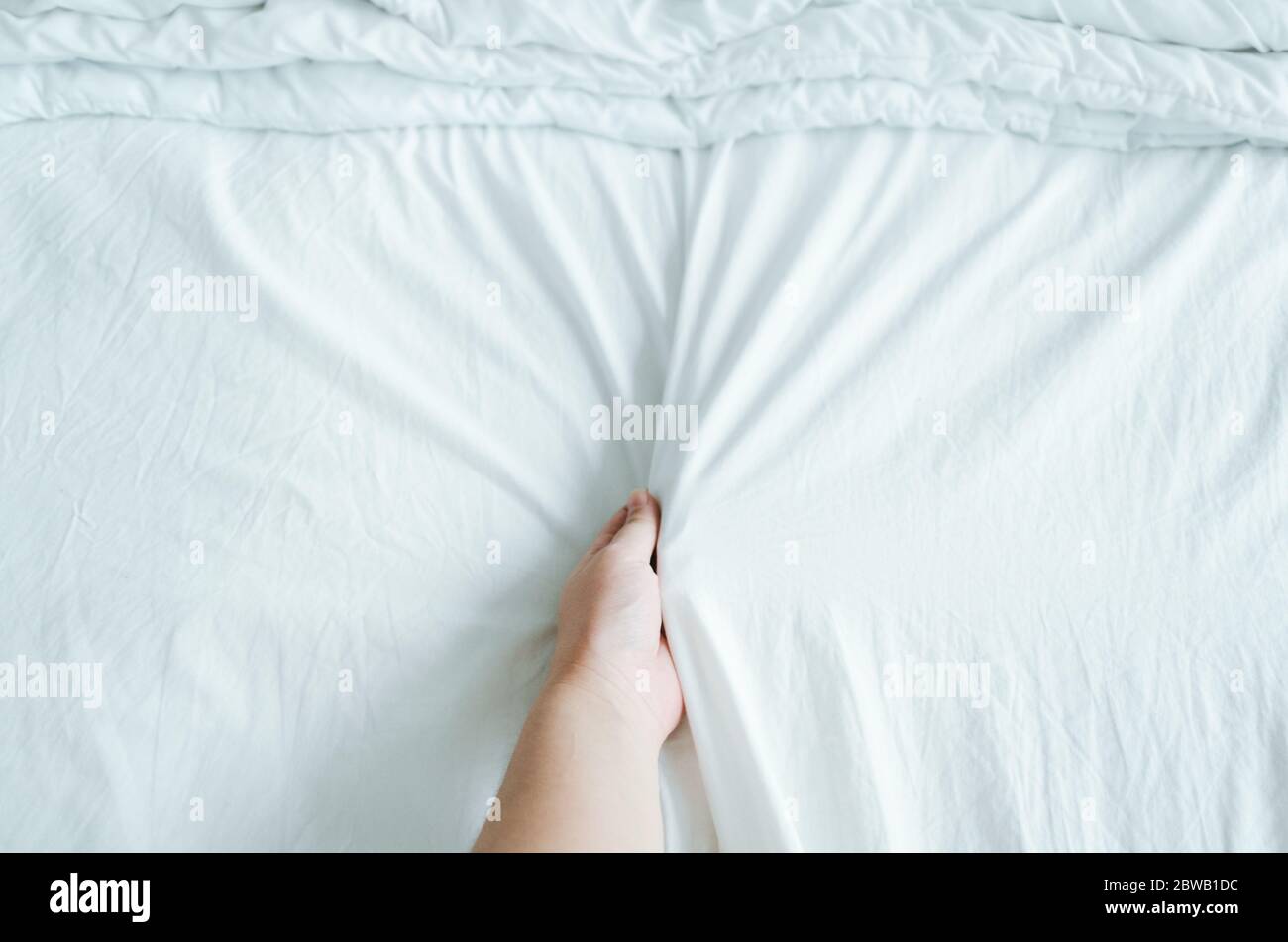 Main exprimant des émotions tout en tenant des feuilles blanches froissées dans le lit. Banque D'Images