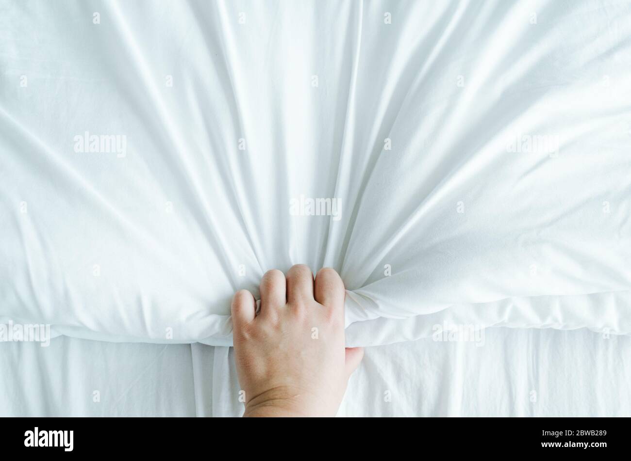 Main exprimant des émotions tout en tenant des feuilles blanches froissées dans le lit. Banque D'Images