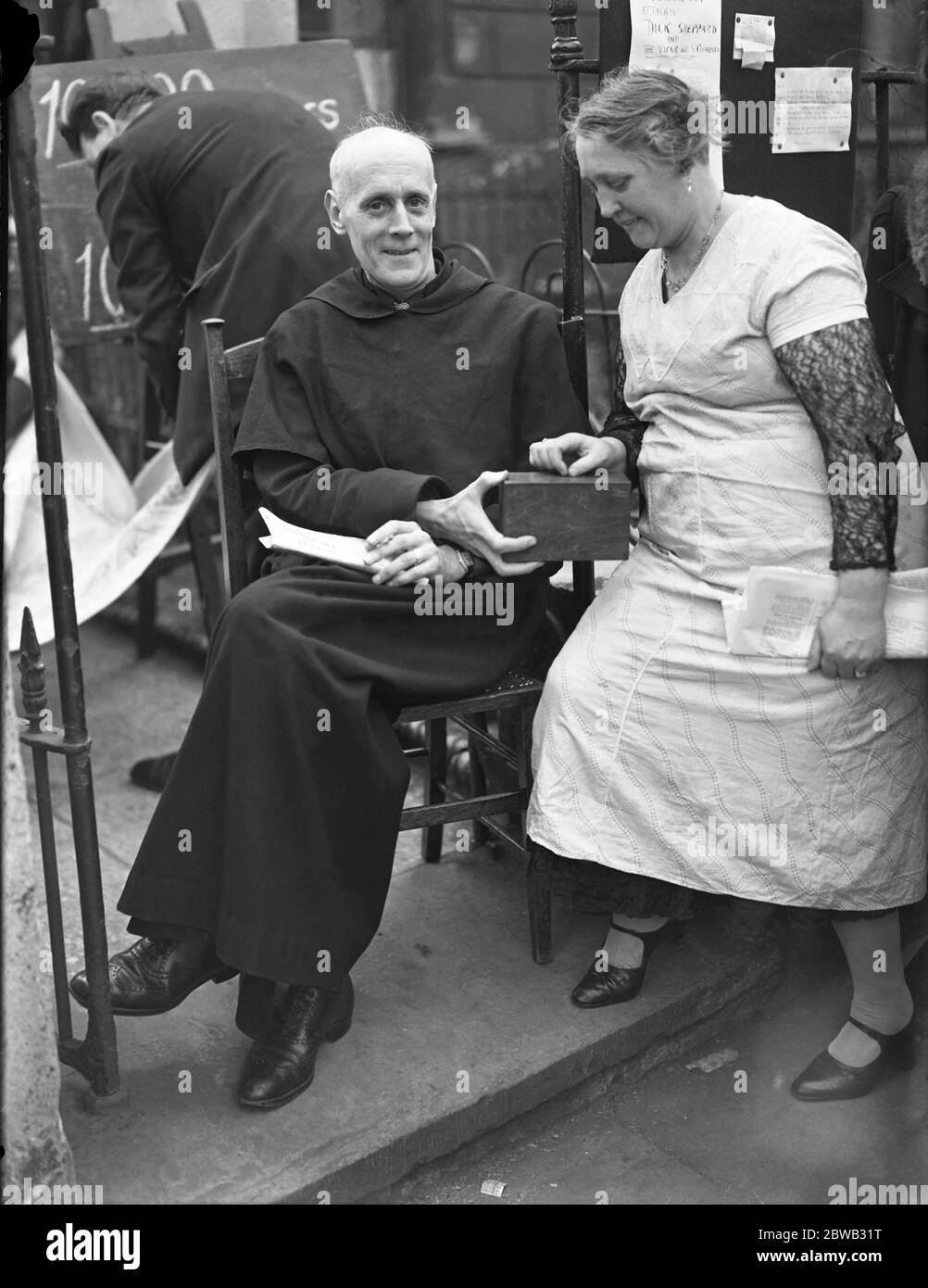 Le révérend E O Iredell assis dans le porche de l' église Saint Clément , Barnsbury , Londres , pour recueillir des dons pour des fonds de l' église . 28 mai 1934 Banque D'Images