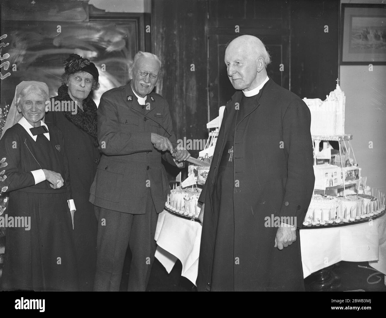 Fondateur de l'Armée de l'Eglise et prébendaire de la Cathédrale Saint Paul , Wilson Carlile coupant son gâteau d'anniversaire lors du déjeuner tenu au quartier général de l'Armée de l'Eglise pour commémorer son 90e anniversaire . Avec lui est l'archevêque de Canterbury , Cosmo Gordon Lang . 14 janvier 1937 Banque D'Images