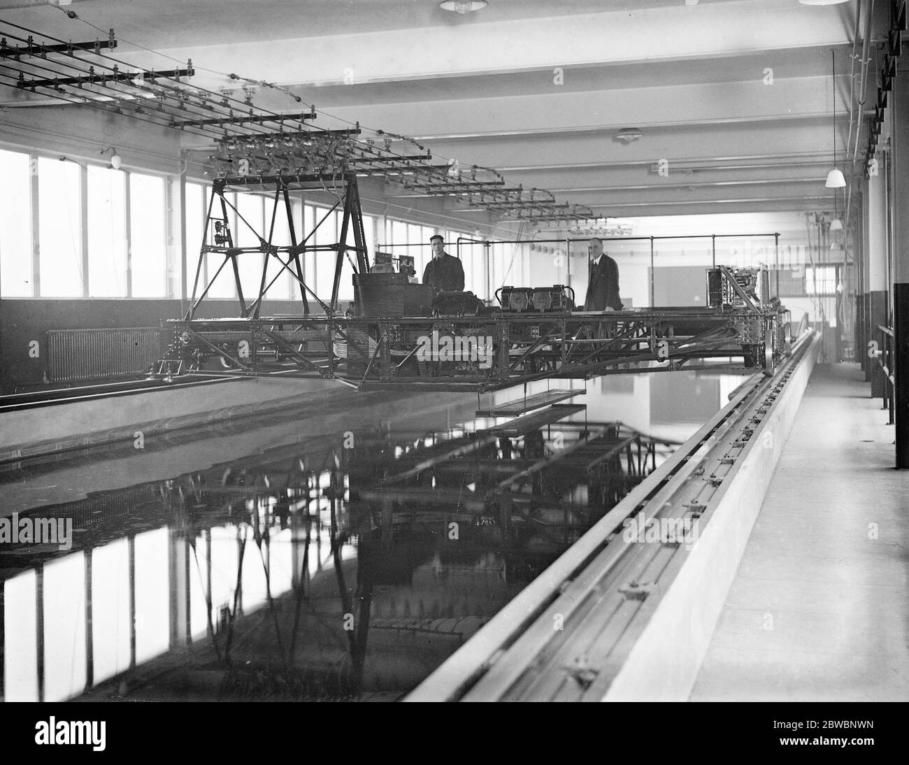 Au Laboratoire physique national , Teddington . Le nouveau réservoir d'essai marin , 678 pi de long , 20 pi de large et profondeur d'eau de 9 pi . Le chariot de remorquage modèle , qui peut remorquer le navire modèle, s'enroule à des vitesses dépassant 30 pieds par seconde . Il est alimenté électriquement par le courant fourni par des fils aériens vus sur la photo . Appareils pour l'essai de hélices . L'hélice est tenue sur un arbre devant le corps et des enregistrements complets pris de son comportement , de sorte que par l'essai de plusieurs la meilleure vis pour n'importe quel navire particulier peut être trouvé . 14 novembre 1932 Banque D'Images