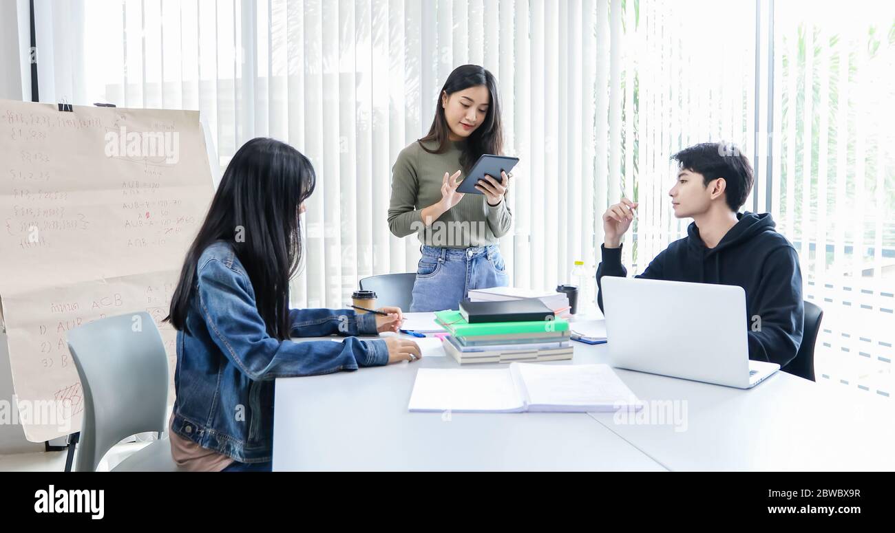 Les étudiants asiatiques lisent des livres et utilisent des tablettes numériques pour trouver des informations pour le travail et les études en ligne Banque D'Images