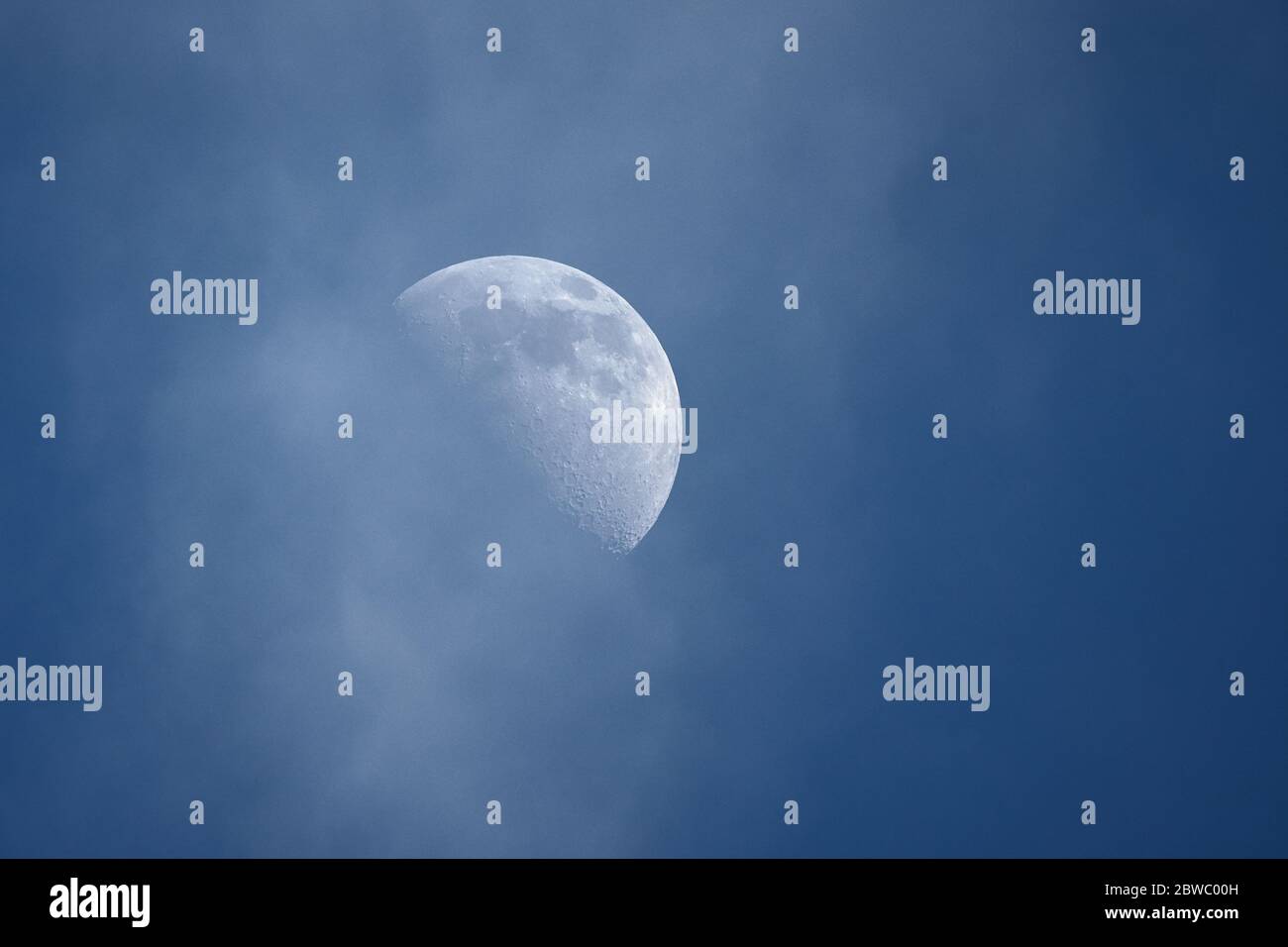 Demi-lune en croissant, premier quart de lune contre ciel bleu nuageux pendant la journée Banque D'Images