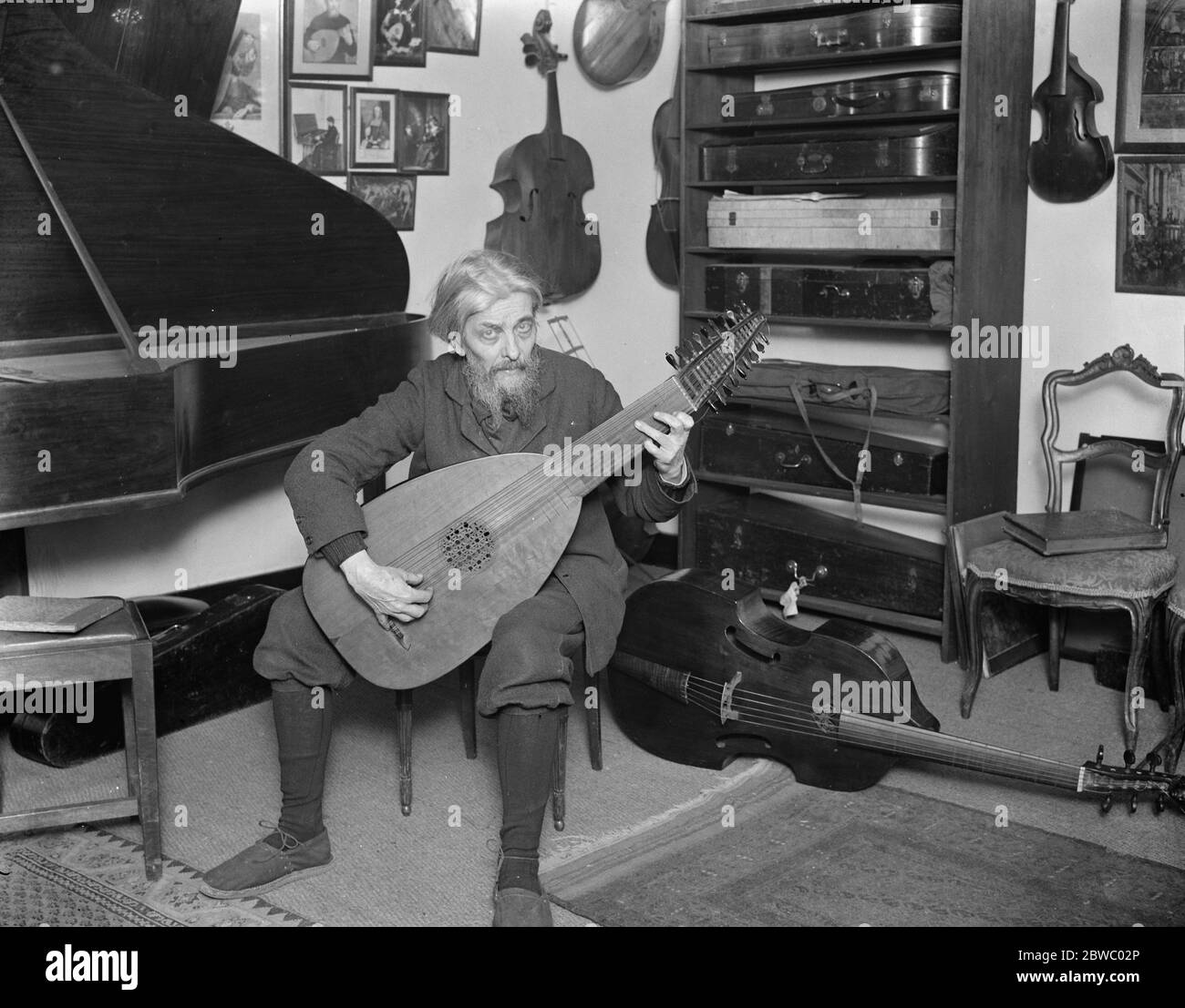 Préparation au festival Haslemere de musique de chambre ancienne . Famille célèbre qui font des instruments de temps vieux . M. Arnold Dolmetsch dans sa salle de musique . Il est vu jouer un luth . 23 janvier 1925 Banque D'Images