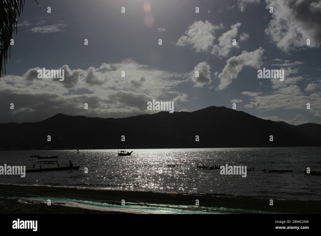 rétroéclairage d'une rive avec des montagnes, des bateaux et des gens Banque D'Images