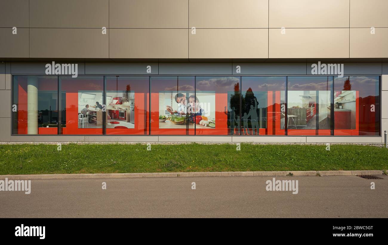 Göppingen, Allemagne - 21 mai 2020: Cuisines Rieger Fasade, panneau rouge réfléchi derrière un mur de verre, rue en premier plan. Goepingen. Banque D'Images