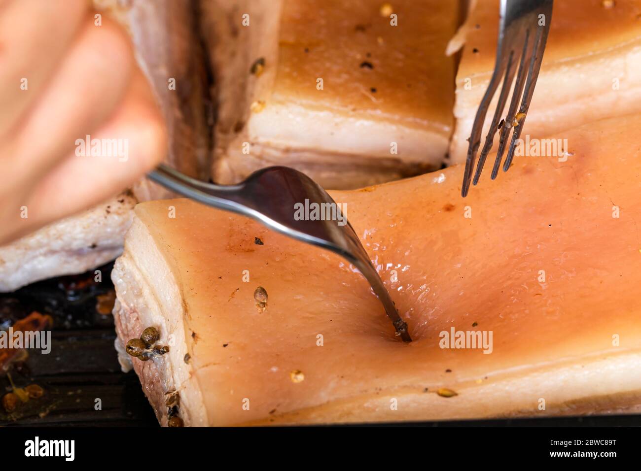 Posture tout en utilisant une fourchette pour percer la peau de porc pour la cuisson. Banque D'Images