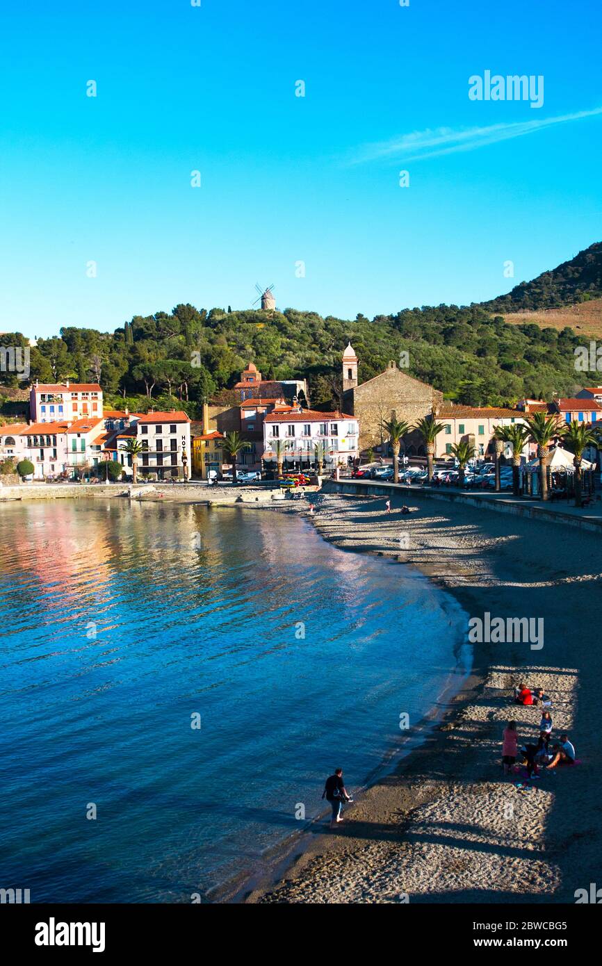 Collioure, France - 24 février 2020: Hôtels de plage à Collioure village avec moulin à vent sur colline, Roussillon, Côte Vermilion, Pyrénées Orientales, Franc Banque D'Images