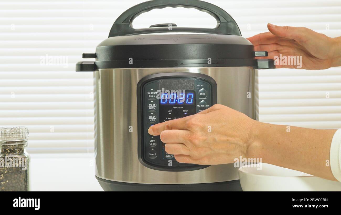Multi cuisinière gros plan sur la table de cuisine. Femme appuyant sur le bouton, le compte à rebours est effectué. Banque D'Images