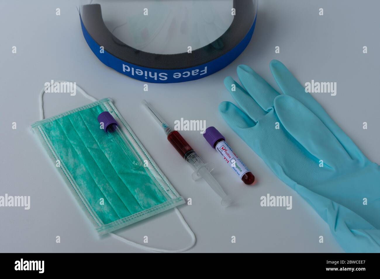 Écran facial, masque chirurgical, gant, seringue et tube à essai contenant un échantillon de sang infecté par le coronavirus. Prévention et traitement du coronavirus Banque D'Images