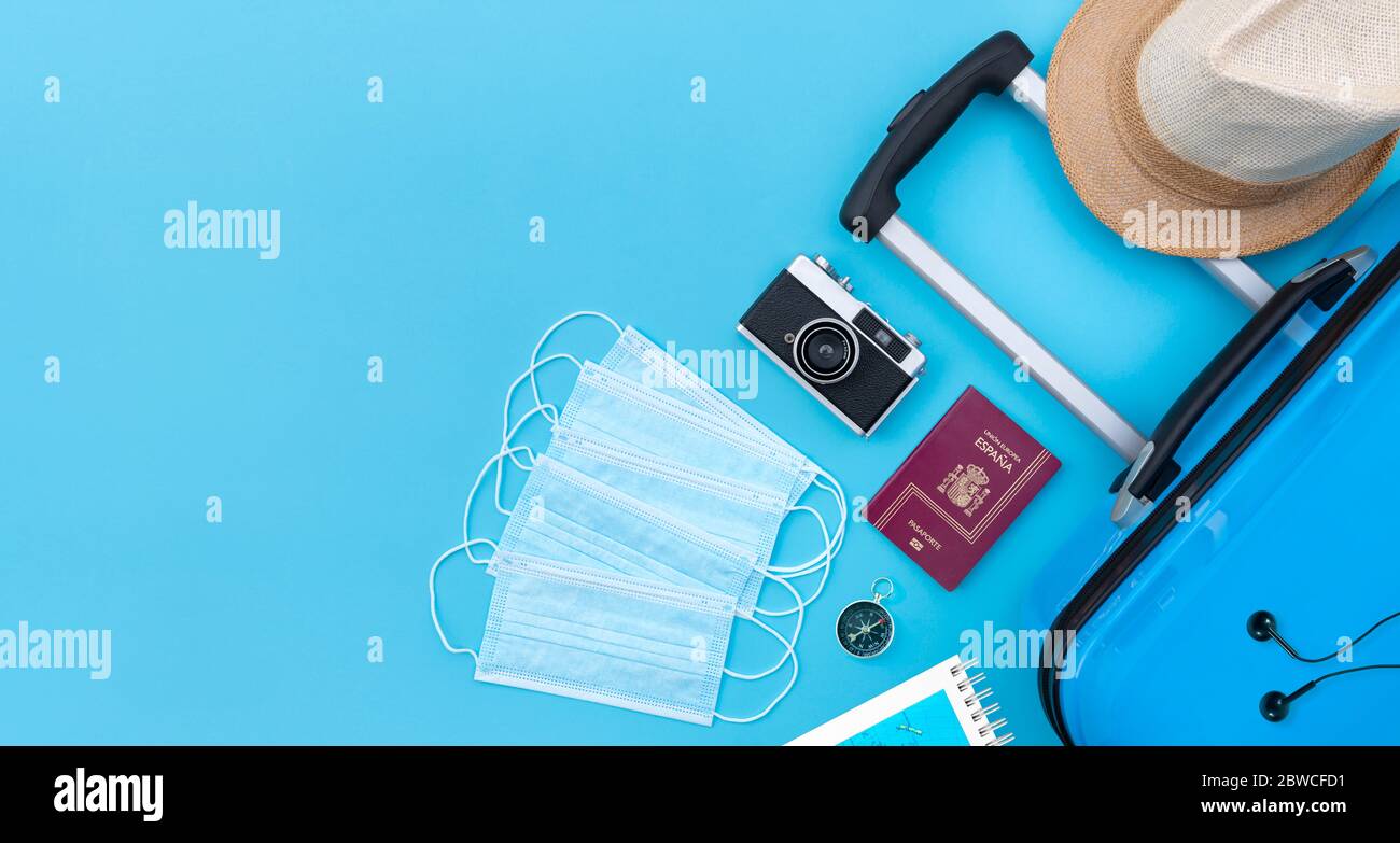 Vue de dessus de la valise et d'autres articles de voyage tels que boussole, appareil photo, passeport et chapeau de paille à côté de l'ensemble de masques médicaux pour la protection de Covid Banque D'Images
