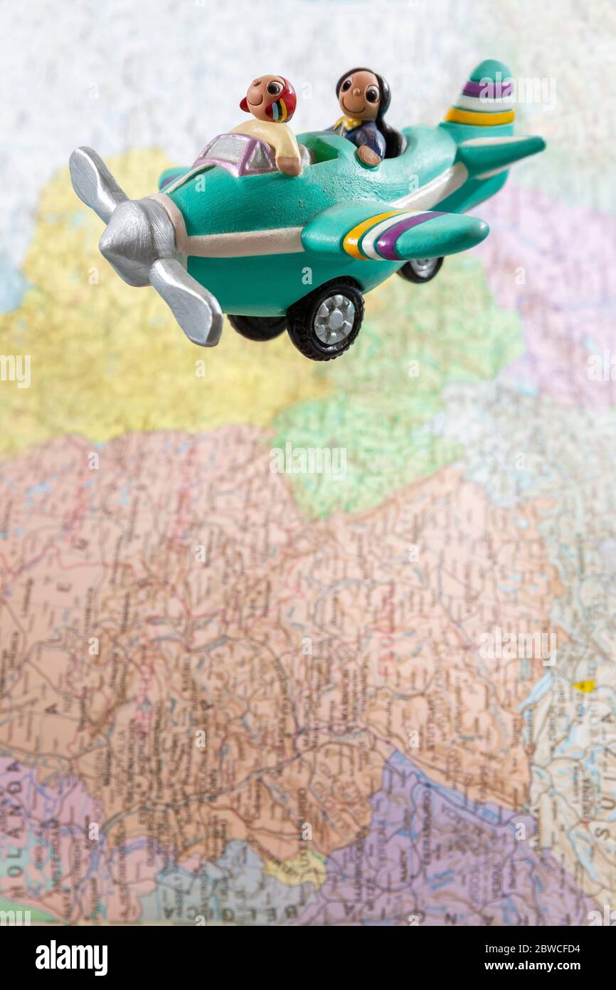 Avion miniature avec deux passagers survolant une grande carte du monde. Espace pour le texte. Concept été, voyage et vacances. Banque D'Images