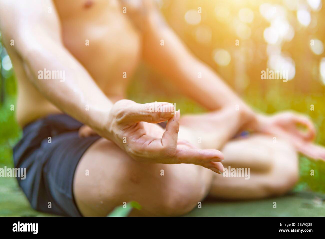 Fermez les mains. Asiatique man do yoga détendez-vous à l'extérieur. Homme exerçant pose vitale et méditation pour le club de style de vie de forme physique à l'extérieur de la nature fond Banque D'Images