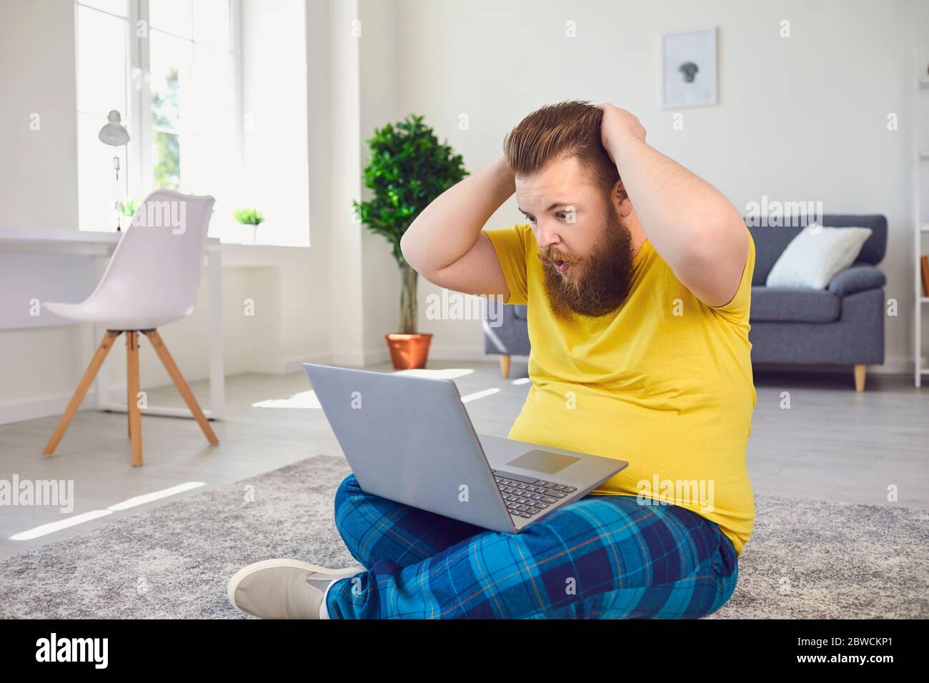 Un homme choqué lisant les nouvelles sur un ordinateur portable dans la chambre Banque D'Images