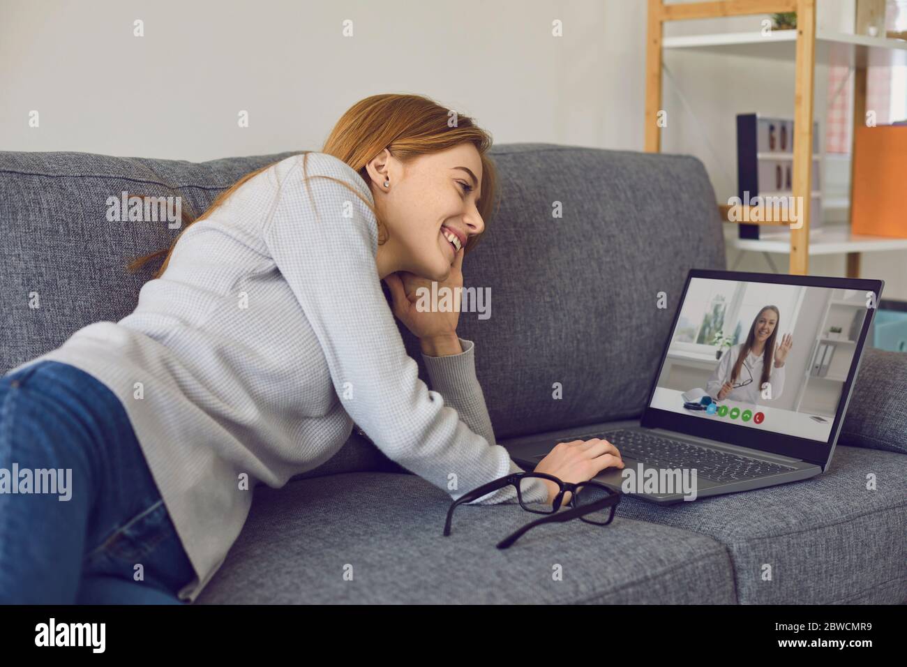 Femme parlant avec un médecin en ligne en utilisant un ordinateur portable à la maison. Jeune patient consultant son thérapeute via Internet Banque D'Images