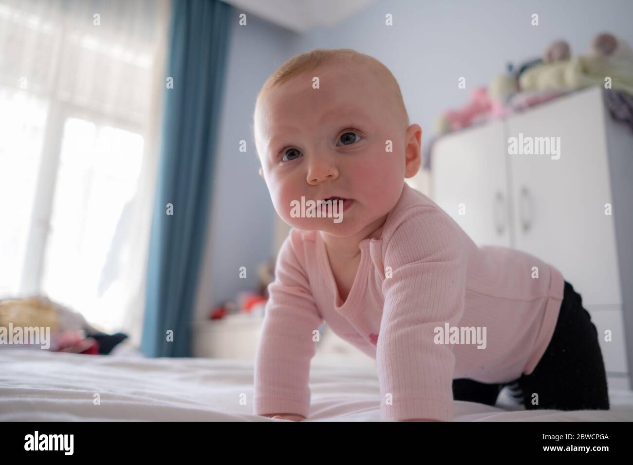 Adorable petite fille debout sur le lit faire des visages drôles, visage en colère, pleurant le matin Banque D'Images