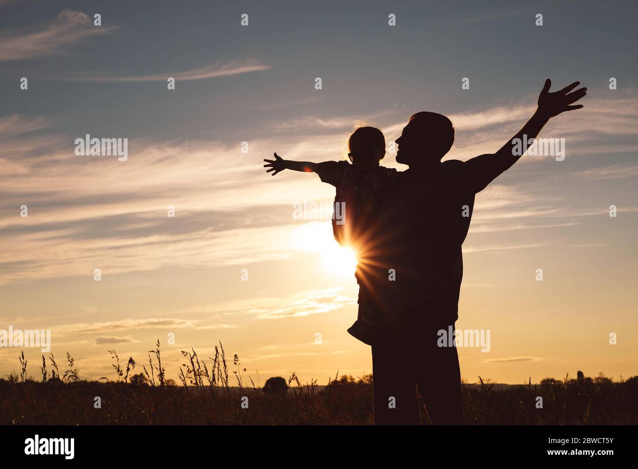 Père et fils jouer dans le parc à l'heure de coucher du soleil. Les gens s'amusant sur le terrain. Concept de famille accueillante et des vacances d'été. Banque D'Images