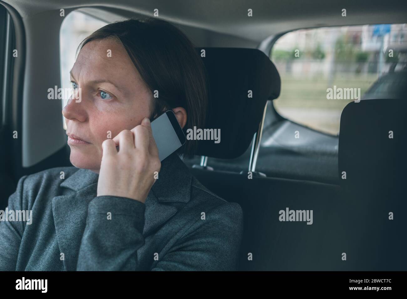 Femme d'affaires déçue en parlant sur le téléphone mobile sur le siège de dossier de voiture, affaires sur le concept de déplacement. Femme caucasienne adulte élégante utilisant le mode Smartph Banque D'Images