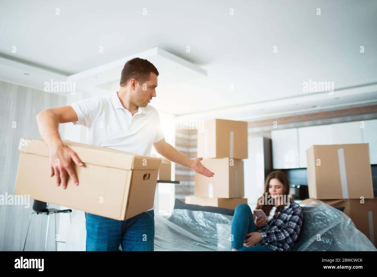 Concept de déplacement et de relation. Il n'est pas satisfait. Le mari déboîte les boîtes. Et la femme ne fait rien pendant ce temps. Elle préfère lui parler Banque D'Images