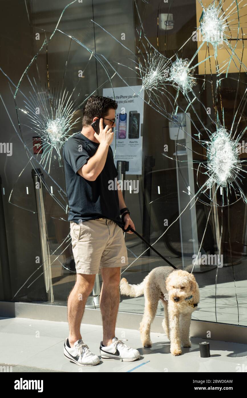 Charleston, États-Unis. 31 mai 2020. Un piéton s'arrête pour voir l'avant de l'Apple Store en verre brisé dans le quartier commerçant de King Street après une manifestation sur la mort de George Floyd, devenu violent et destructeur le 31 mai 2020 à Charleston, Caroline du Sud. Floyd a été étouffé par la police à Minneapolis, ce qui a entraîné des manifestations qui ont balayé le pays. Crédit : Richard Ellis/Alay Live News Banque D'Images