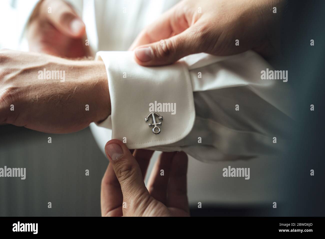 Meilleur homme aidant le marié à s'habiller. Manches de chemise réglables à mains masculines avec boutons de manchette à ancre. Banque D'Images