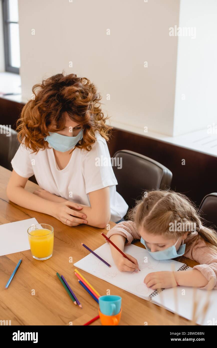 mère dans un masque médical regardant le dessin d'enfant à la maison Banque D'Images