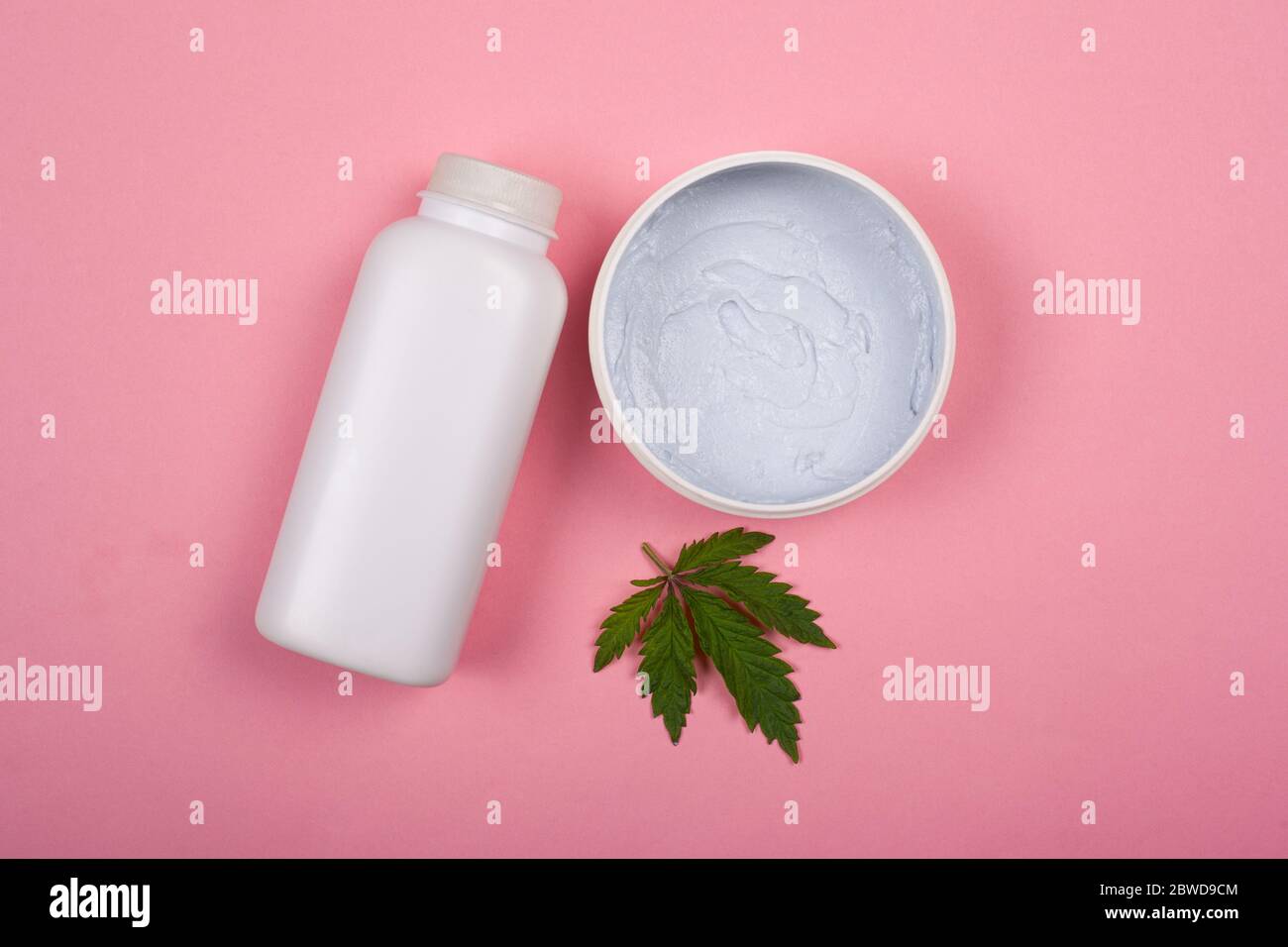 bouteilles blanches avec cosmétiques pour le corps avec une feuille de marijuana sur fond rose vue du dessus. soins de la peau, beauté, cosmétiques avec cannabis. Banque D'Images