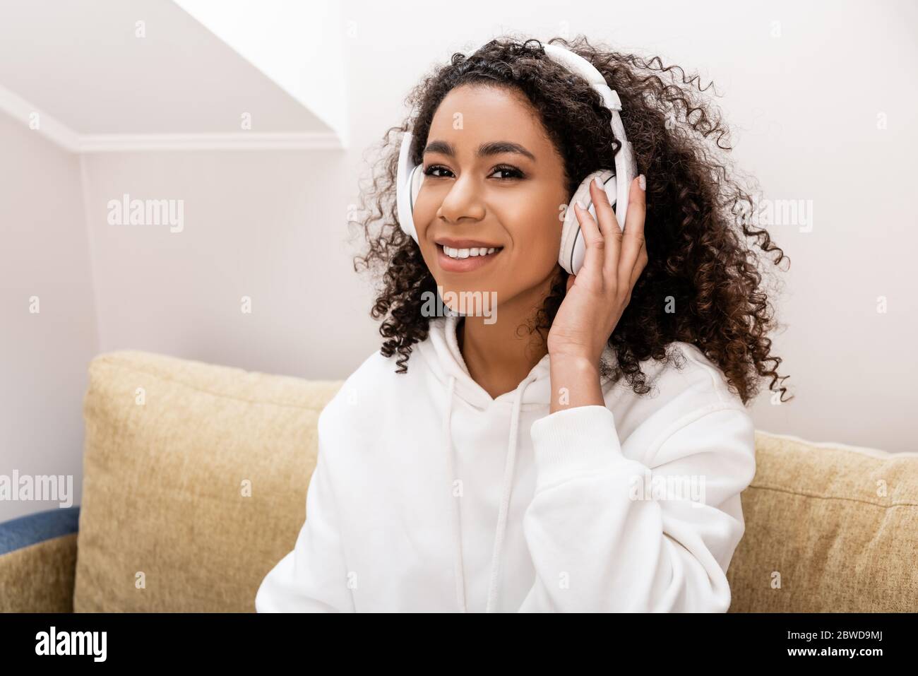 bonne fille afro-américaine dans un casque sans fil qui écoute de la musique à la maison Banque D'Images