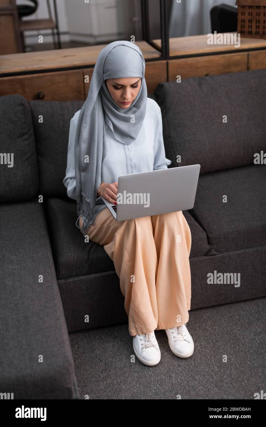 femme arabe dans hijab utilisant un ordinateur portable dans le salon Banque D'Images