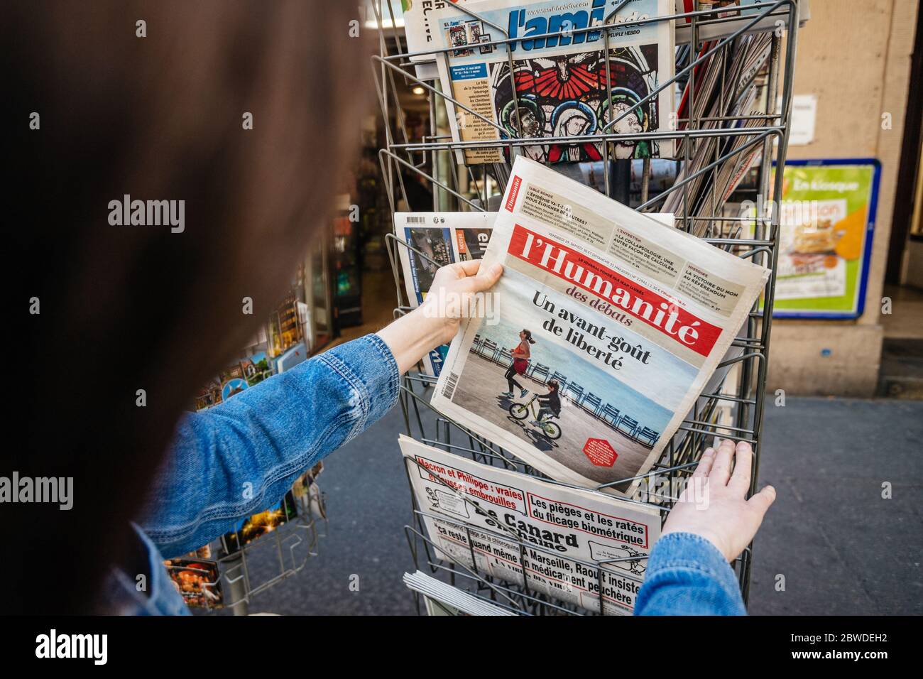 Paris, France - 30 mai 2020 : une femme portant un masque acheté au kiosque de presse l'humanité, journal français présentant des zones de distance sociale dans un parc américain vert Banque D'Images