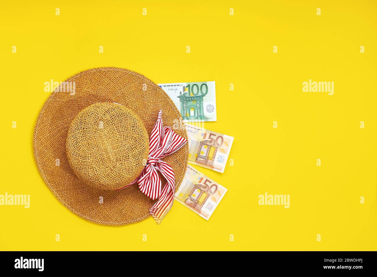 Chapeau de paille avec des billets d'euro isolés sur un fond jaune. Vue de dessus de l'appartement. Concept de dépenses en espèces de vacances Banque D'Images